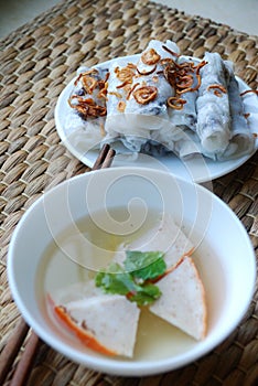 Banh cuon-vietnamese steamed rice rolls with minced meat inside and pieces of vietnamese ham accompanied by bowl of fish sauce.