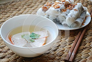 Banh cuon-vietnamese steamed rice rolls with minced meat inside and pieces of vietnamese ham accompanied by bowl of fish sauce.