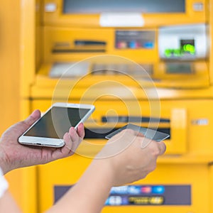 Bank ATM Auto Teller Machine with customer user person using credit card, or debit card and smartphone for paying cash payment