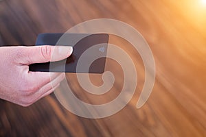 Bank card in hand, on a wooden background, the concept of business, home buying.