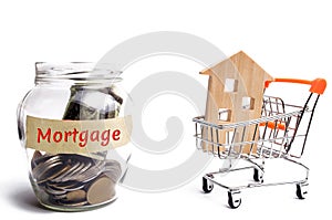 Bank with coins and the inscription Mortgage and a house in a trolley supermarket. Buying a house or apartment loans. Payment of