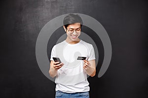 Bank, finance and payment concept. Portrait of cheerful asian man in t-shirt, holding mobile phone and credit card