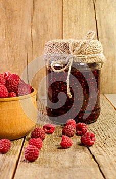 Bank of raspberry jam and fresh raspberries