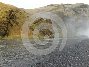 Bank of SkÃ³gÃ¡ river veiled in mist emanating from the SkÃ³gafoss waterfall