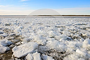 Bank of a wide river with pieces of ice and snow during an ice drift