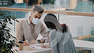 Bank worker in medical mask businessman salesman insurance man realtor manager talking with female client woman advises