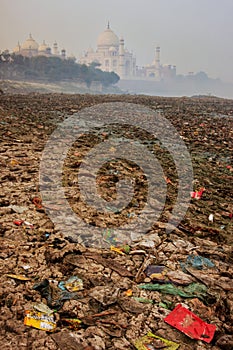 Bank of Yamuna river covered with garbage and Taj Mahal in a fog in the background, Agra, Uttar Pradesh, India