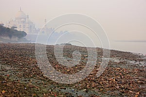 Bank of Yamuna river covered with garbage and Taj Mahal in a fog photo