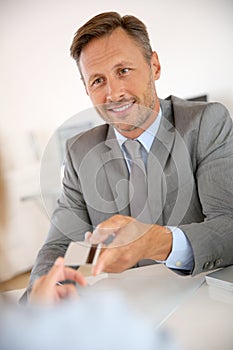 Banker with grey suit holding credit card