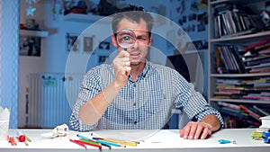 Banker looks through a magnifying glass, grimaces with his tongue, grimaces