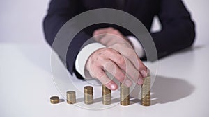 Banker putting coin on pile, deposit interest growing, successful investment