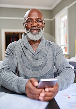 This banking app is wonderful. Cropped portrait of a senior man using his cellphone while working on his finances at