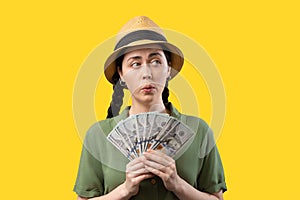 Banking and exchange currency. Portrait of a amazement Caucasian woman wearing straw hat and holding a fan of dollars