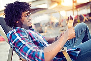 Banking online, portrait of happy black business man with tablet on the beach