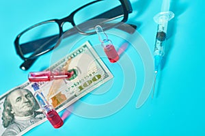 Banknote of 100 usd, glasses, vaccine and syringe on green background. Corruption in medicine