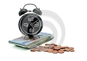 Banknote and coins with alarm clock on white background.