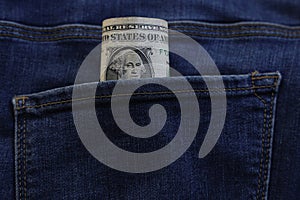 Banknote of north american one dollar bill in blue jeans pocket background. bill of 1 american bucks sticking out of the back