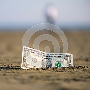 Banknote of value of one dollar in the the sand on the beach. Concept of cheap travel and vacation.