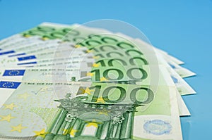 Banknotes of 100 euros are beautifully laid out on a blue background. Euro money. Financial concept.