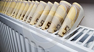 Banknotes of 50 euros stick out of the radiator battery. The concept of rising heating costs in the winter cold season