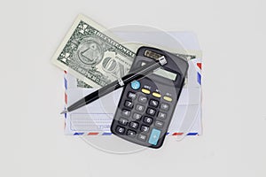 Banknotes in airmail envelope and black pen with calculator on white background