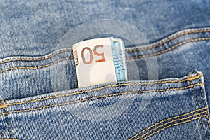Banknotes bills of Euro currency sticking out of the blue jeans pocket.