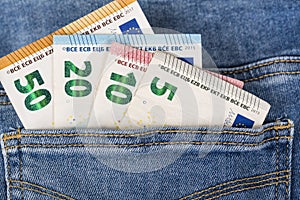 Banknotes bills of Euro currency sticking out of the blue jeans pocket.