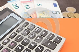 Banknotes and calculator. Euro banknotes on wooden background. Photo for tax, profit and costing.