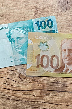 Banknotes of canadian currency: Dollar and brazilian Currency: Real. Bils on wood rustic table.Dollar and brazilian Currency: Real