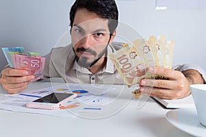 Banknotes of Canadian currency: Dollar. Business man offerign bills and looking at camera