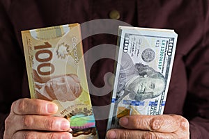 Banknotes of canadian currency: Dollar and North American Currency: US Dollars. Old retired person paying in cash.