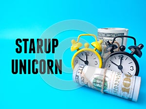 Banknotes and clock with text STARUP UNICORN