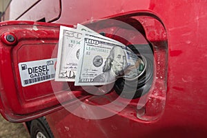 Banknotes, dollars in the fuel filler of a red car