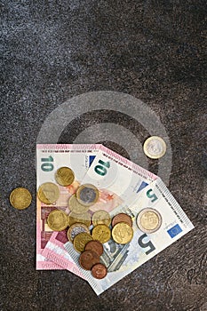 Banknotes of euros and coins eurocents lie on a dark stone background, crisis and inflation