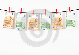 banknotes hanging on a clothesline against white background. Euro money with red clothes pegs on rope. Money Laundering euro hung