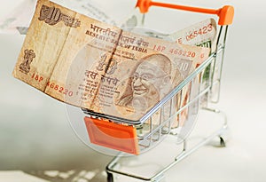 Banknotes with indian leader Mahatma Gandhi inside shopping mall trolley. Idea of the consumer ability in modern India