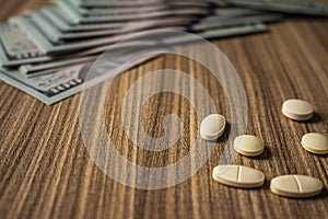 Banknotes and medicines on a desk. Health cost concept. Money and drugs for legal use