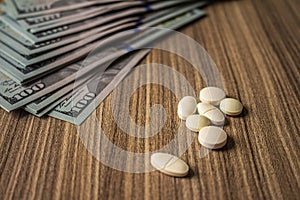 Banknotes and medicines on a desk. Health cost concept. Money and drugs for legal use