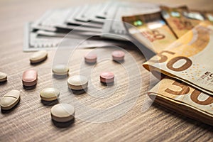 Banknotes and medicines on a desk. Health cost concept. Money and drugs for legal use