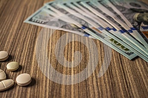 Banknotes and medicines on a desk. Health cost concept. Money and drugs for legal use