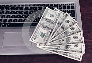 Banknotes over laptop keyboard dollars money