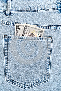 banknotes in the pocket of blue jeans. five dollars bills.