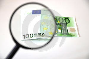 Banknotes spread out on a table with a calculator and a magnifying glass.