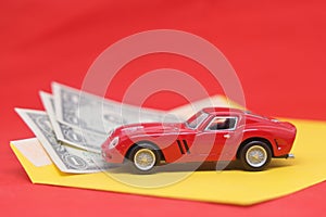 Banknotes in a yellow envelope and a red toy car, funds for the purchase of a car, auto insurance and a car loan.