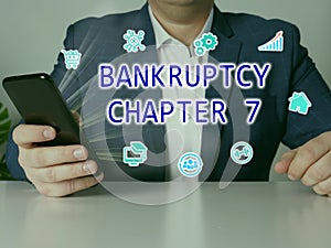 BANKRUPTCY CHAPTER 7 inscription on the screen. male hands holding black smart phone