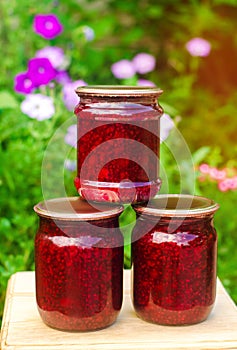 Banks with fragrant homemade raspberry jam in the garden. summer harvest. sweet food. food stock for the winter. countryside, outd