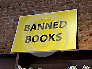 Banned Books sign against brick wall on top of bookshelf