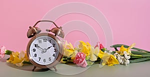 Banner with alarm clock with spring flowers. Spring time, daylight savings concept, spring forward