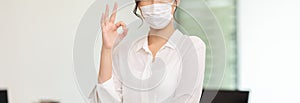 Banner of Asian business women leader wearing mask protection virus standing smile making okay and confidence at Co-Working space