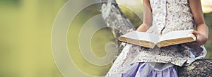 Banner Asian Girl holding book reading at green park in nature garden. Panorama Young todler girl relaxation read book. Happy